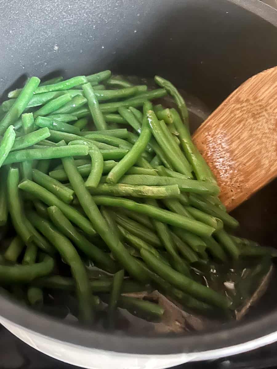 Add cooked green beans to the sauce.