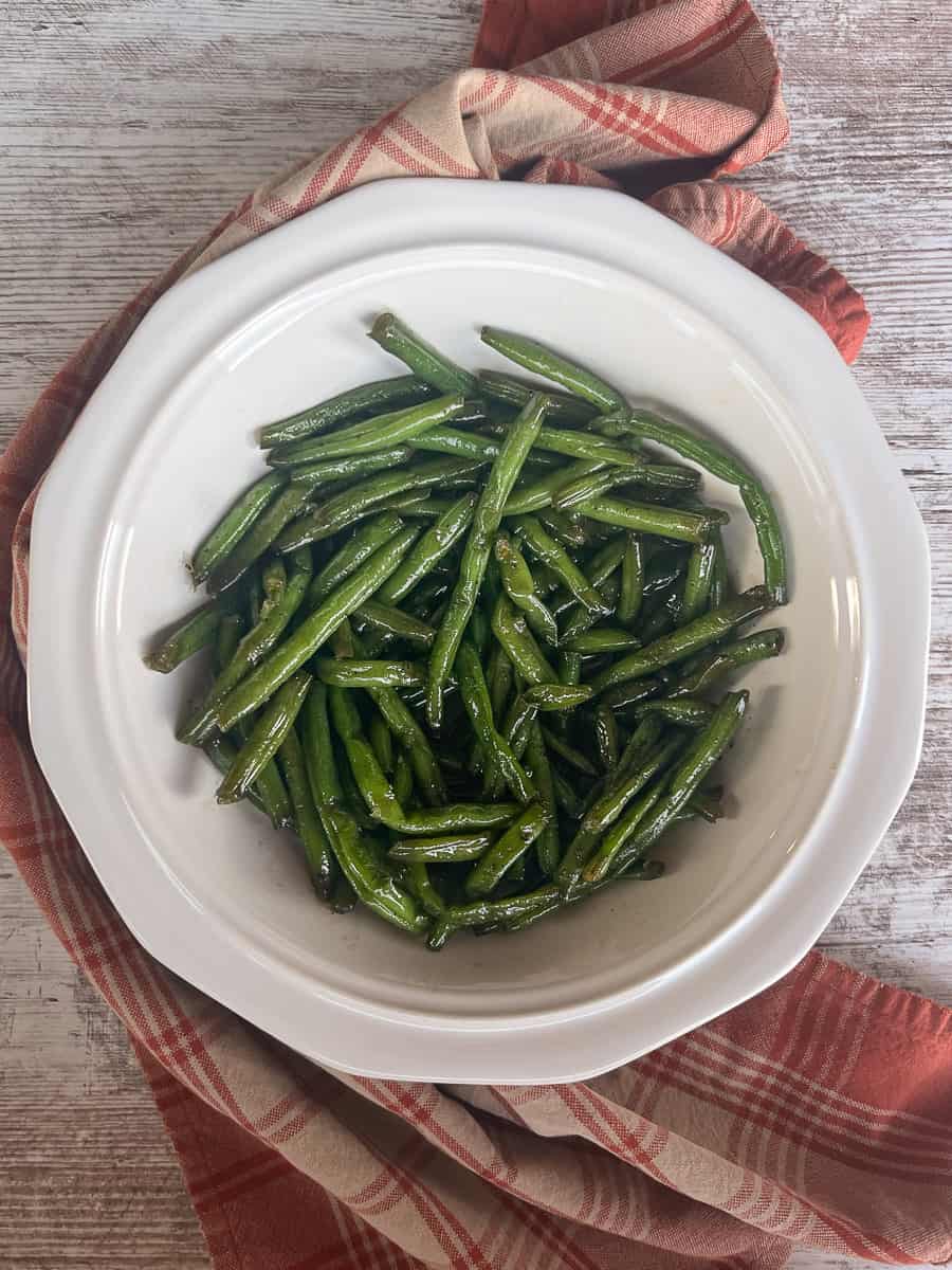 Glazed sweet and salty green beans in a white serving dish.
