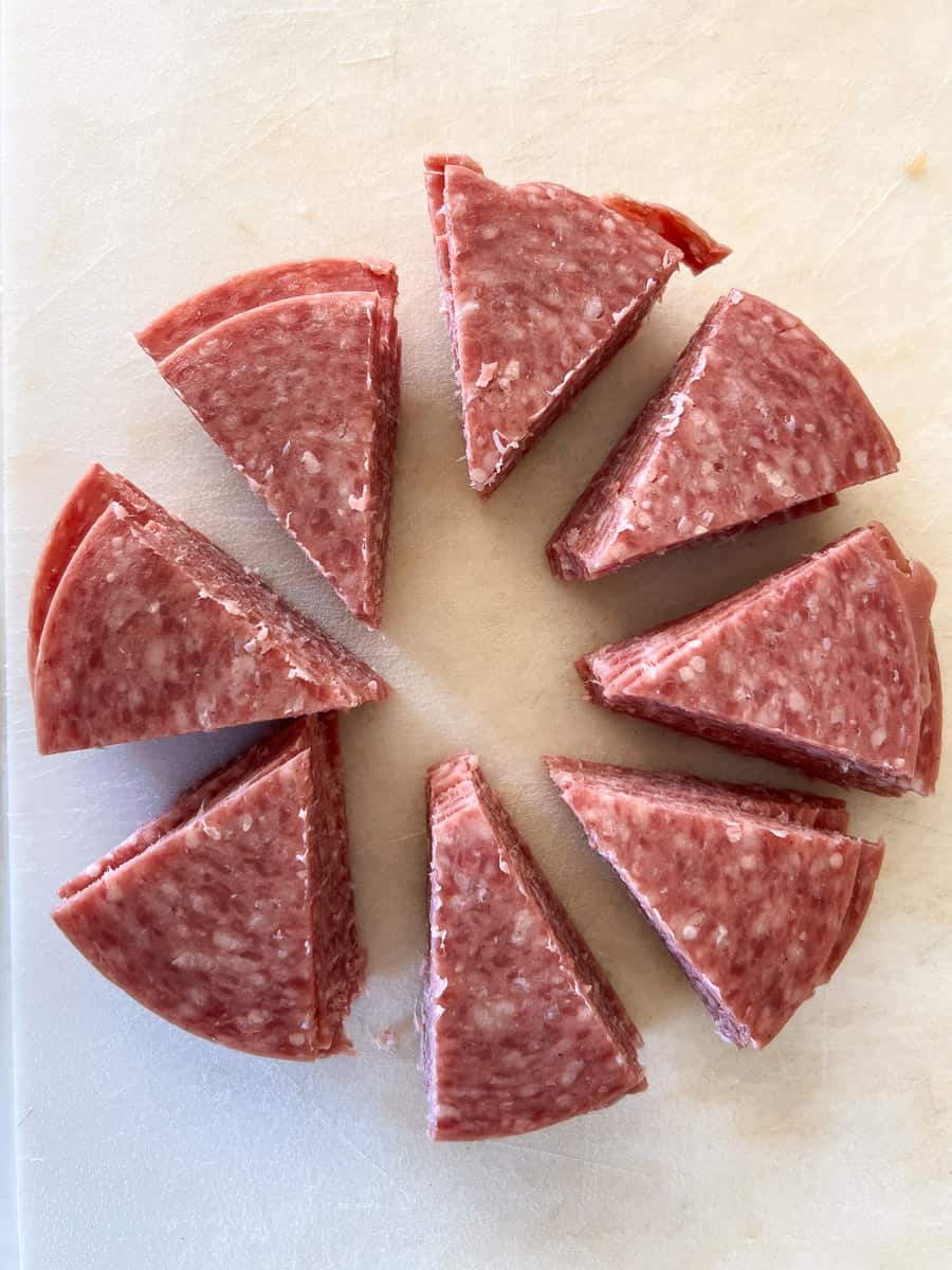 salami cut into triangles on a cutting board.