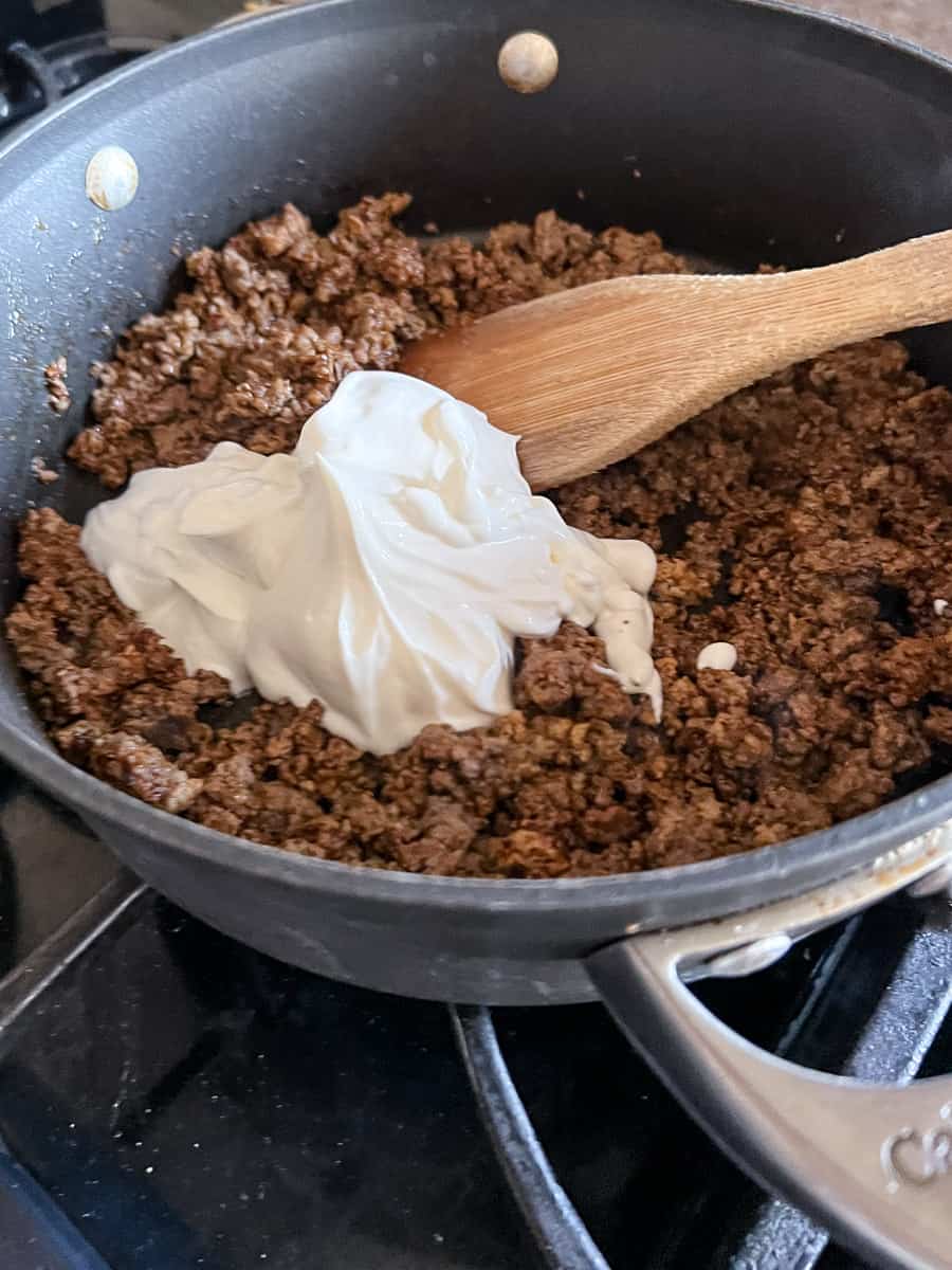 Add sour cream to the seasoned ground beef. 