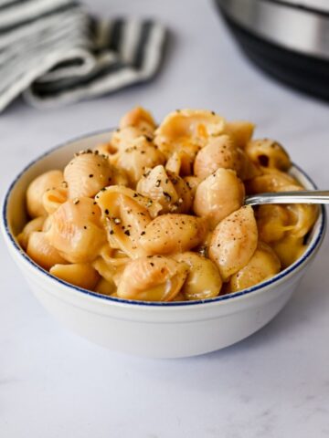 bowl of mac and cheese with a spoon in it alongside an instant pot.