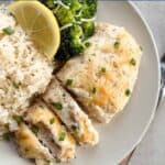 sliced chicken breasts on a plate with a side of rice and broccoli.