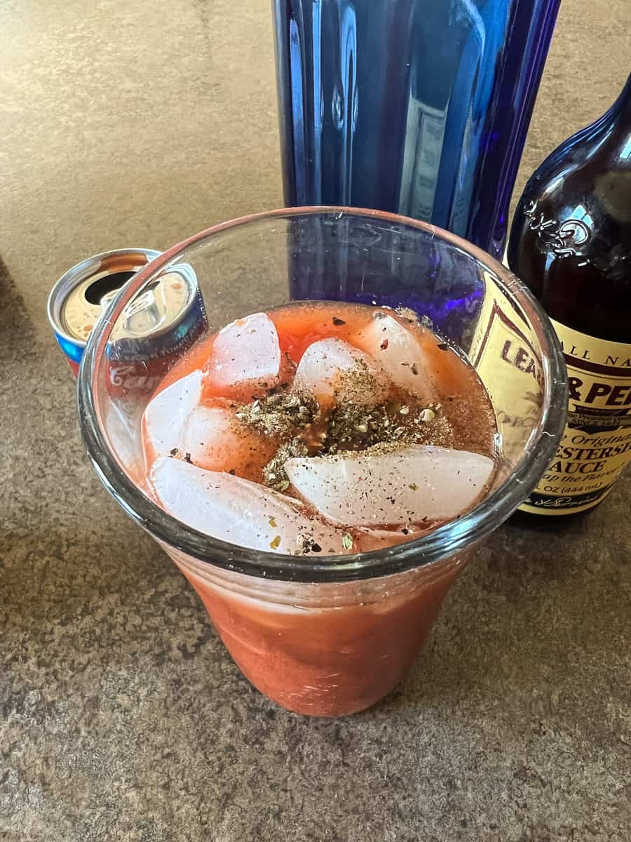 spices on top of the tomato juice in glass.