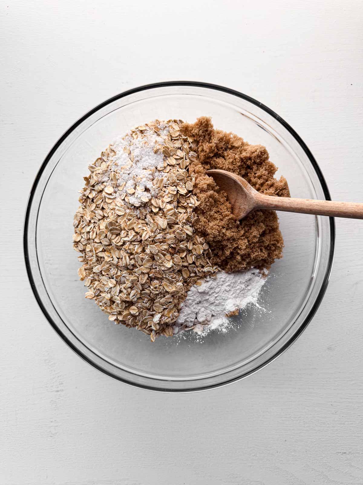 dry ingredients in a glass bowl with a wooden spoon.