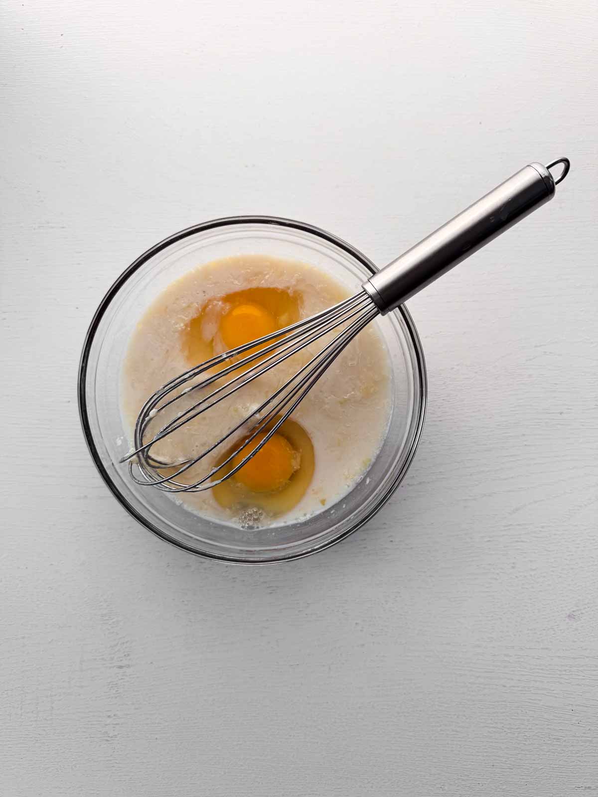 glass bowl with wet ingredients with whisk.