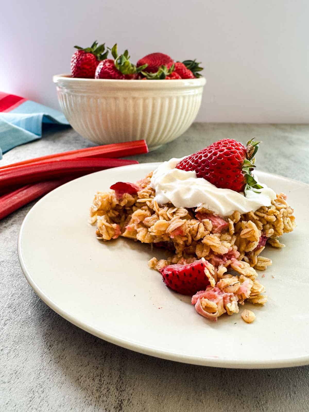 plate of baked oatmeal topped with whipped cream and a bowl of strawberries. 