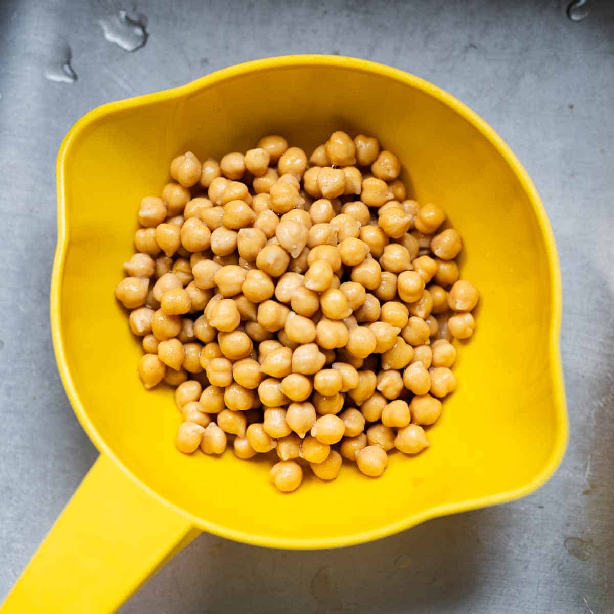 canned chickpeas in a yellow strainer.