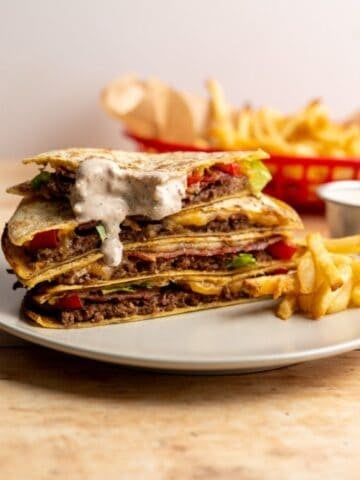 stacked smashed quesadilla burgers with Mexi-ranch drizzled down the stack.