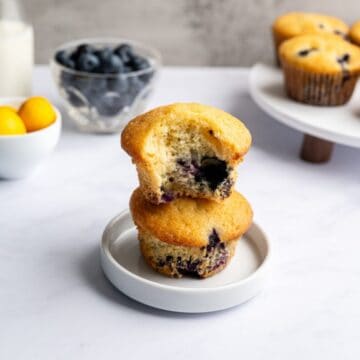 two muffins stacked with the top one missing a bite.
