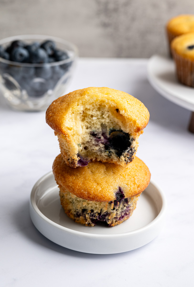 two stacked blueberry muffins on a small white plate. 