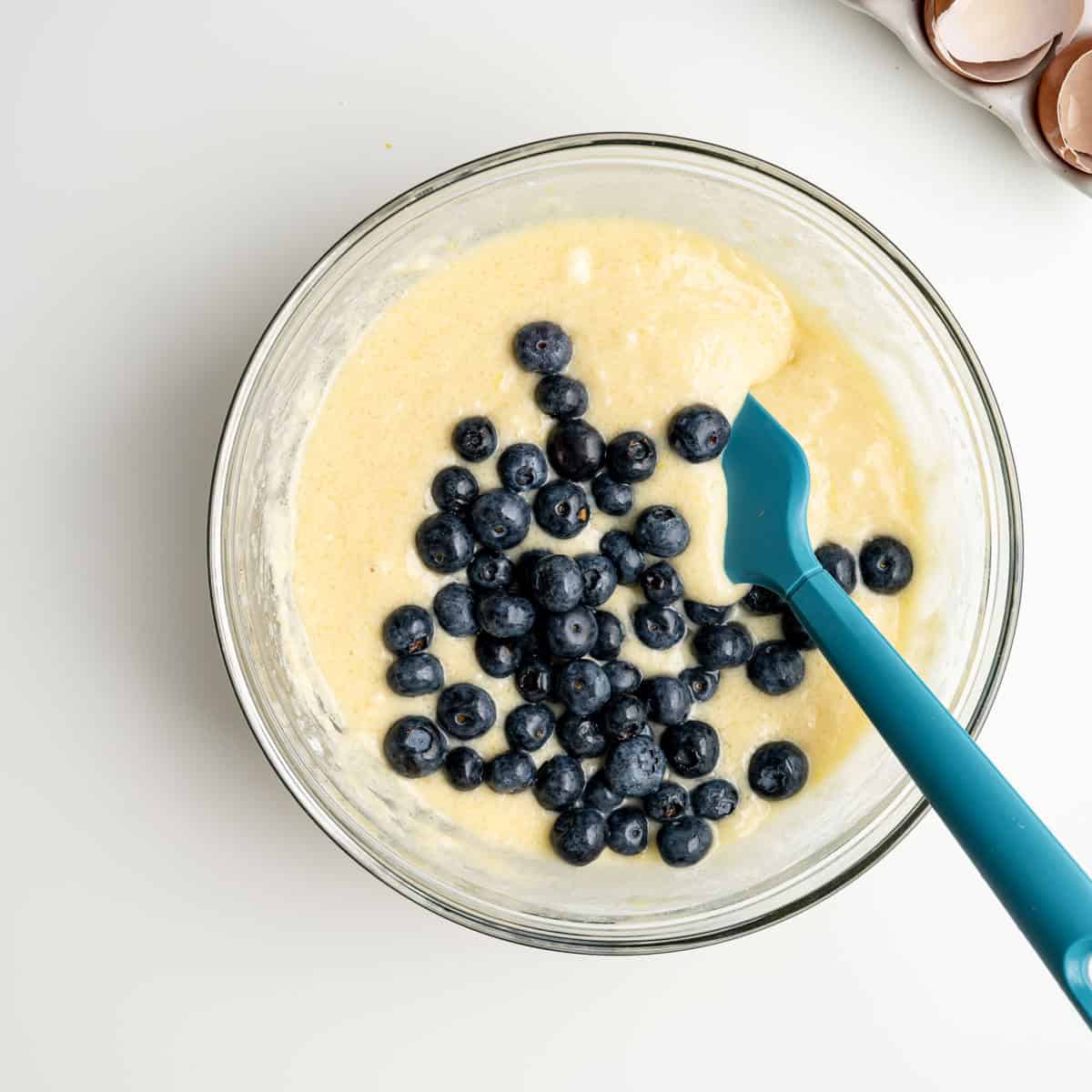 fresh blueberries add to the muffin batter with a blue spatula.