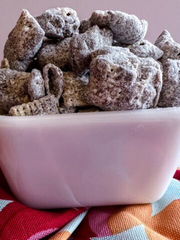 puppy chow in a white bowl on a colorful napkin.