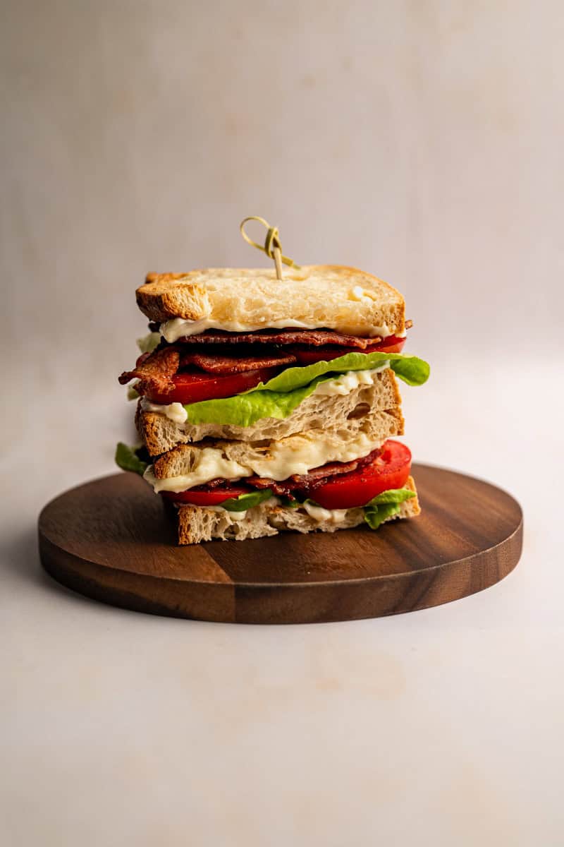 stacked BLT with cottage bacon, lettuce and tomatoes on a wooden board.