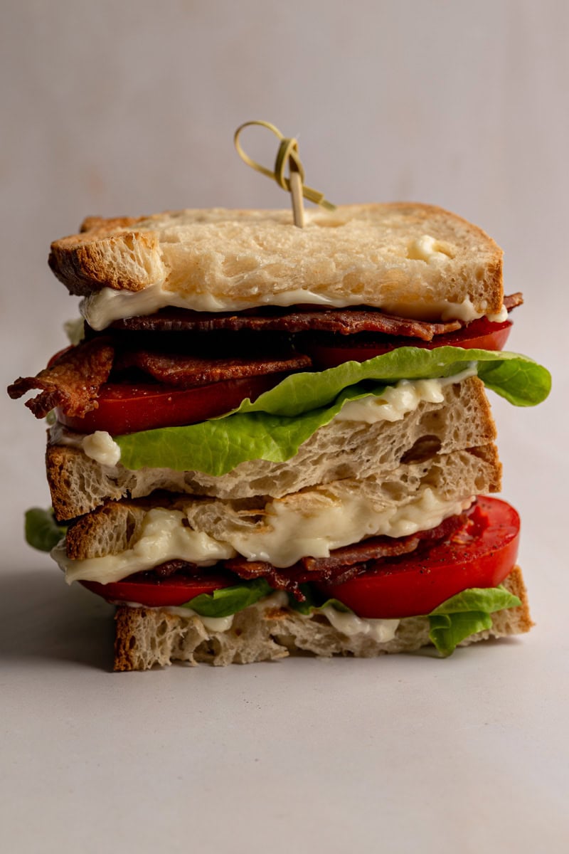 stacked and layered BLT sandwich on a table.
