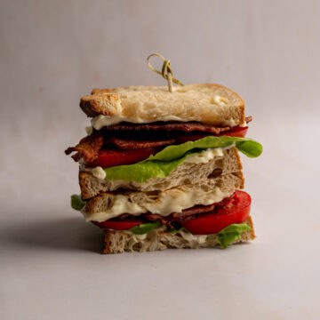 stacked BLT sandwich on a table.