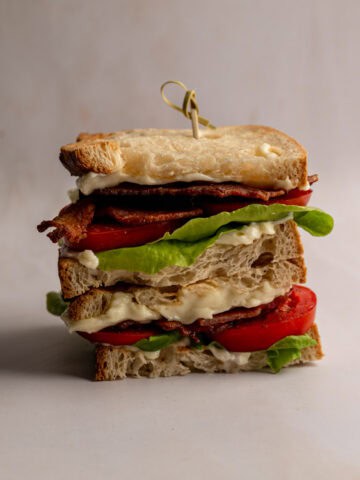 stacked BLT sandwich on a table.