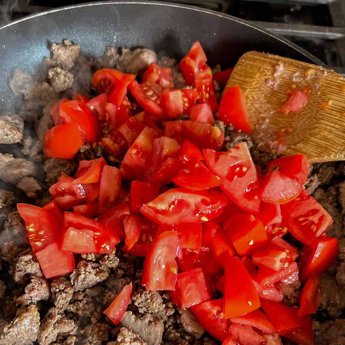 ground beef and Italian turkey with chopped tomatoes in a skillet.