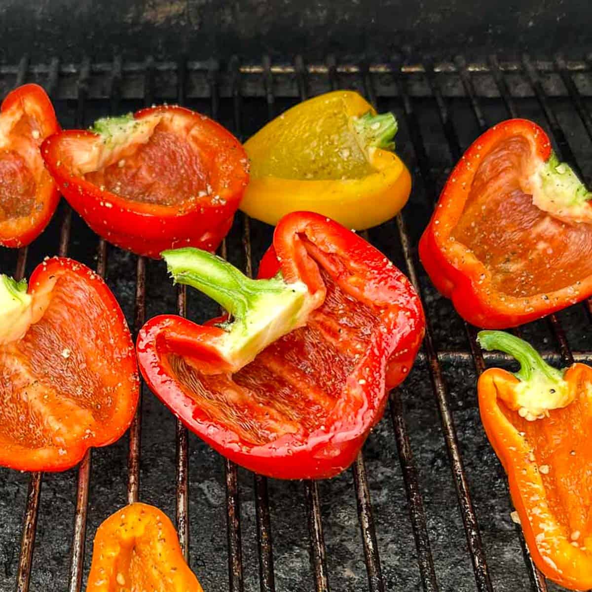halved peppers brushed with garlic oil and sitting on grill grates.