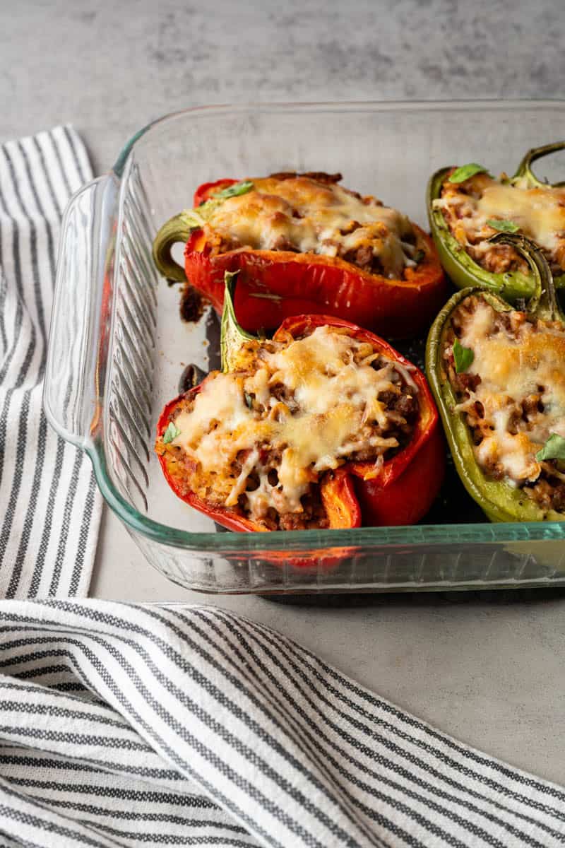 four stuffed peppers in a glass baking dish.