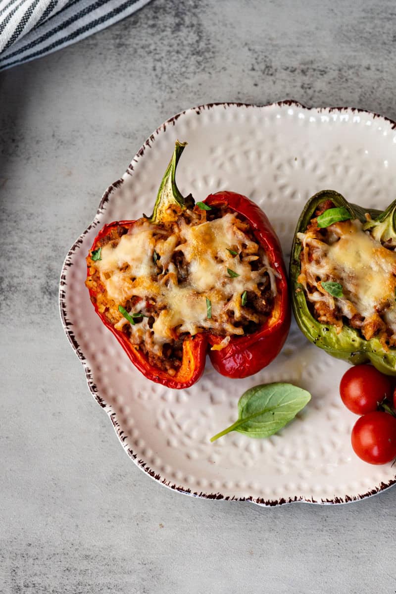 halved bell peppers stuffed and topped with melted cheese on a white plate.