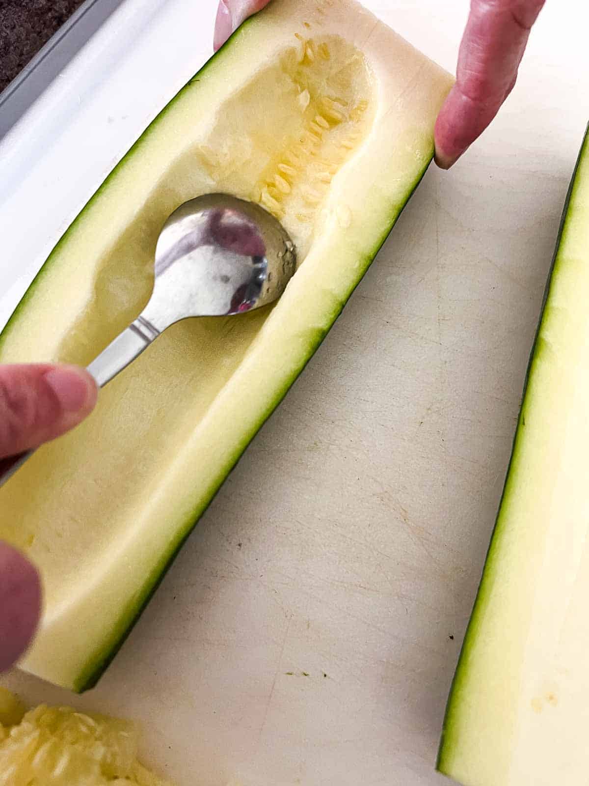 small spoon scooping out the inside of the zucchini halves.