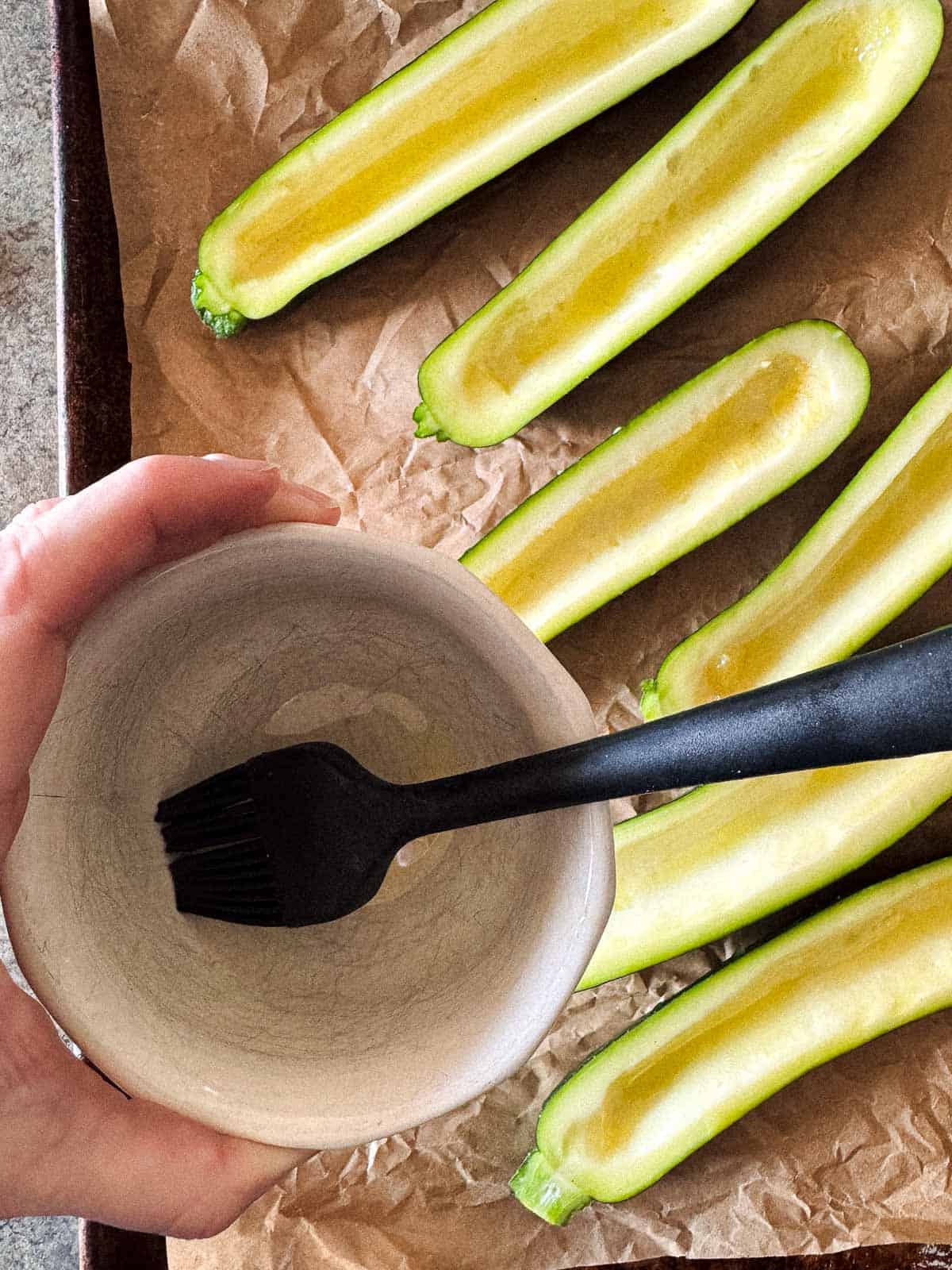 small brush in a small bowl to brush the olive oil on the zucchini halves on a baking sheet. 