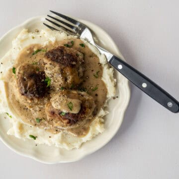 plate of dairy free swedish meatballs piled on top of mashed potatoes with a fork.