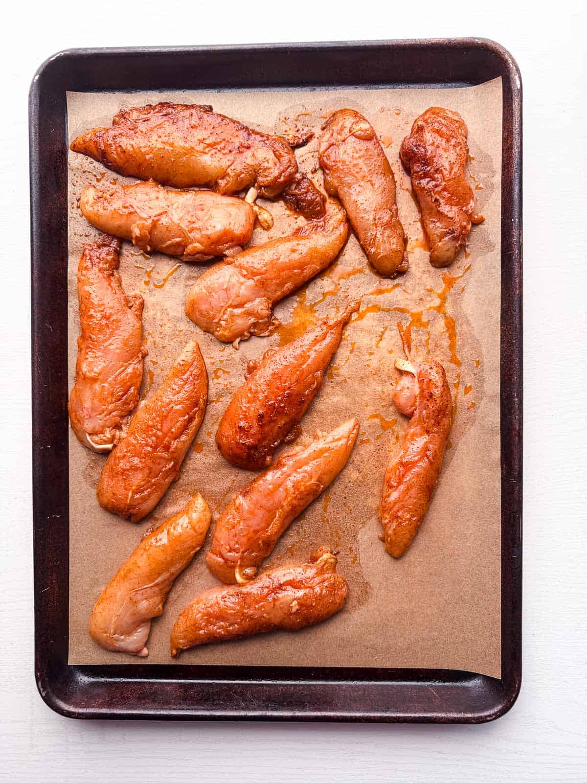 marinated chicken tenders on a baking sheet.