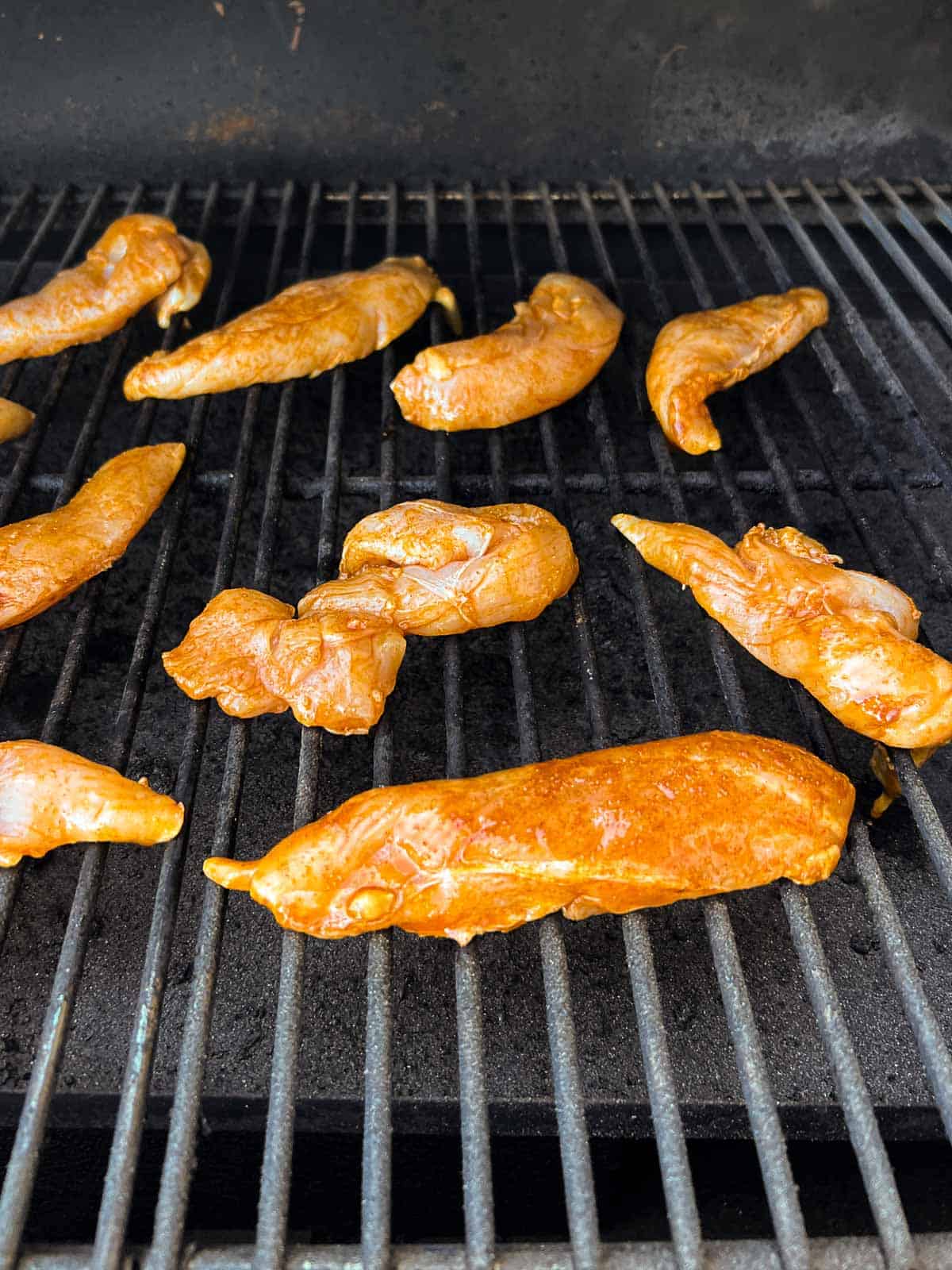 chicken tenders on grill grates.