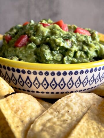 guacamole in a colorful bowl surrounded by tortilla chips.