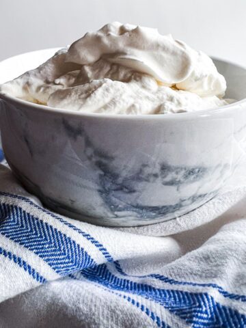 a marbled white bowl full of whipped cream and a blue and white towel.