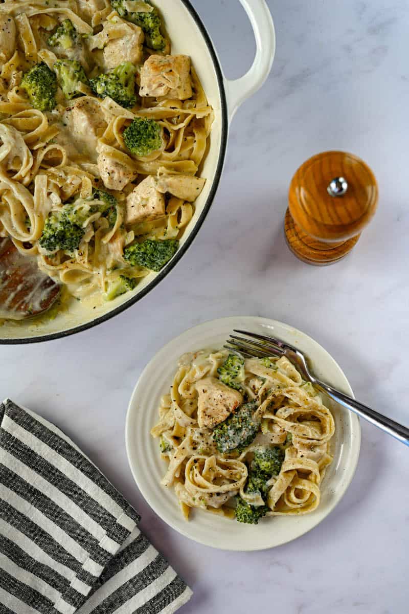 overhead view of chicken alfredo in a plate and a dish with a pepper grinder.