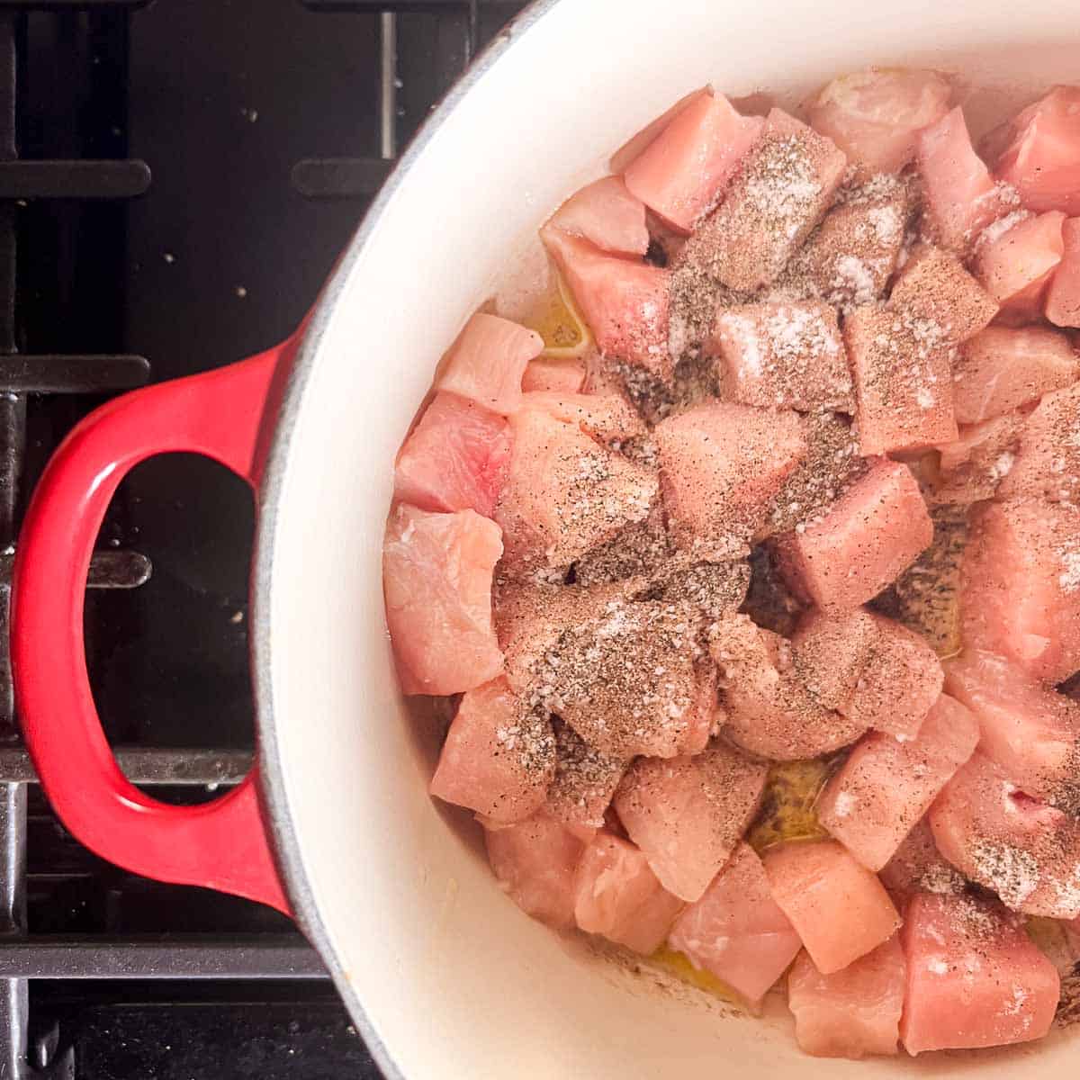 diced chicken in a red dutch oven.
