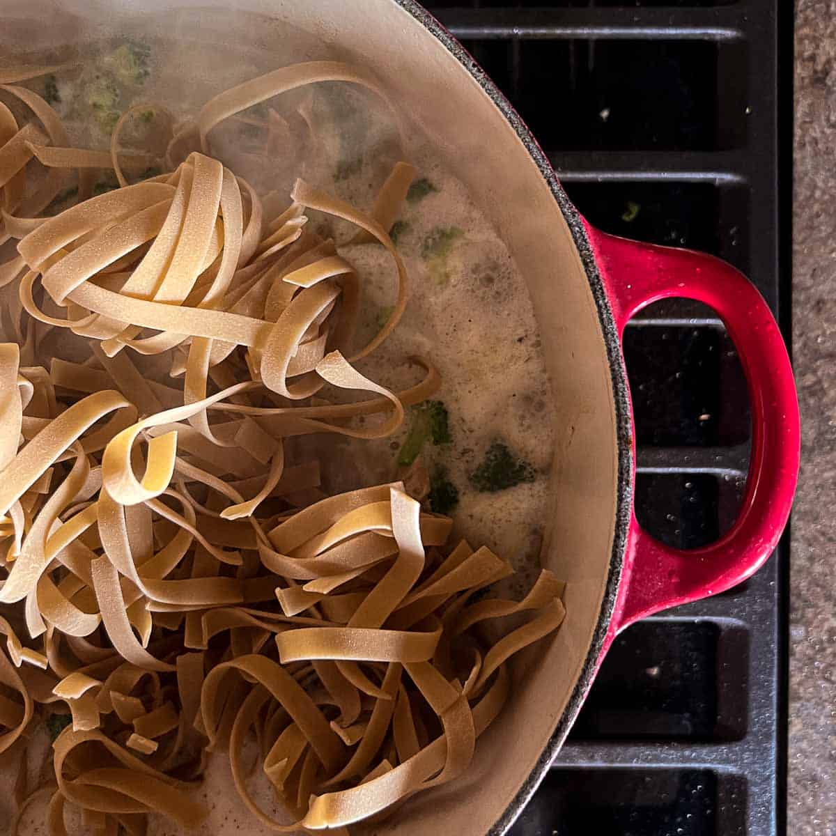 gluten free noodles in a red dutch oven on the stovetop.