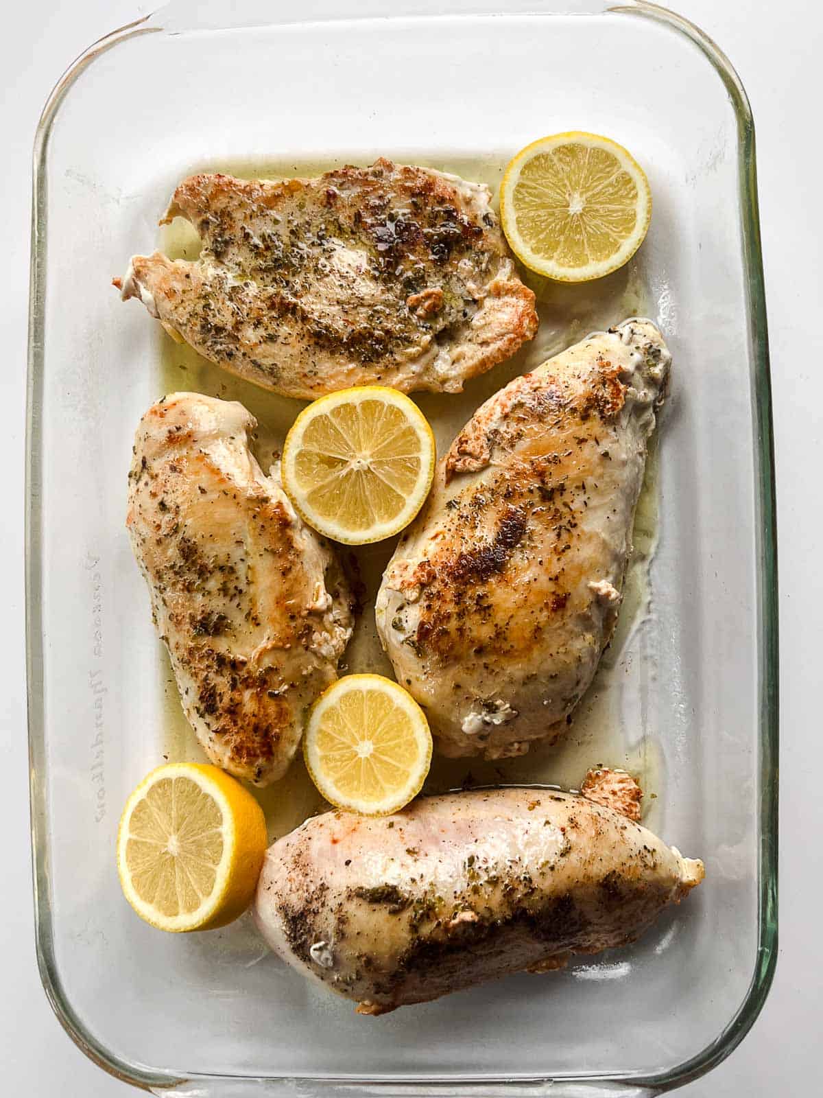 golden brown chicken breasts in a baking dish with lemon slices.