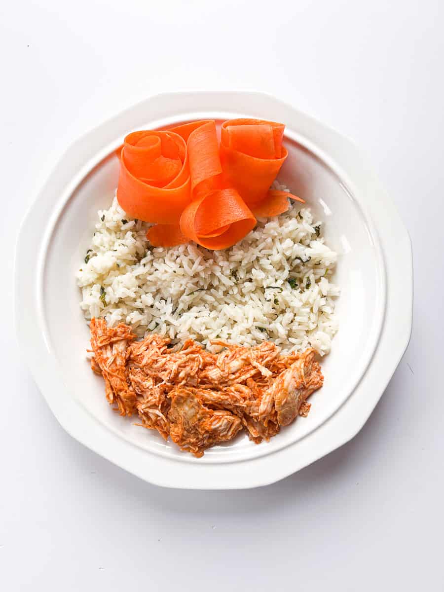 white bowl with cilantro lime rice, buffalo chicken and carrots.