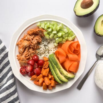rice bowl in a white bowl with a side of ranch dressing and a halved avocado.
