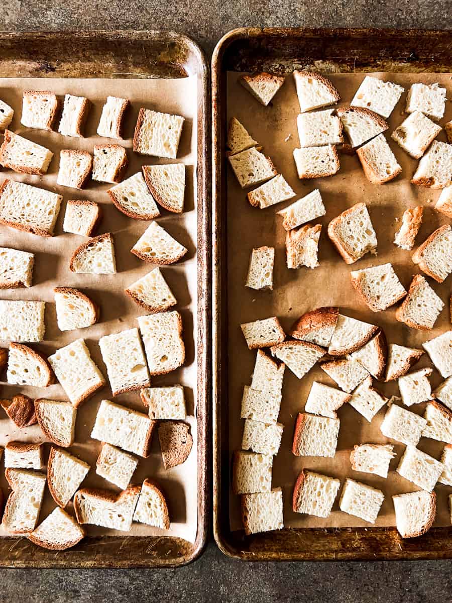 two baking sheets with bread cubes.