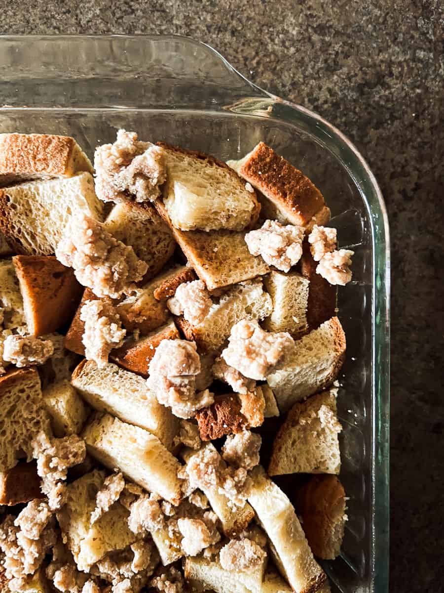 streusel topping on bread cubes in glass pan.