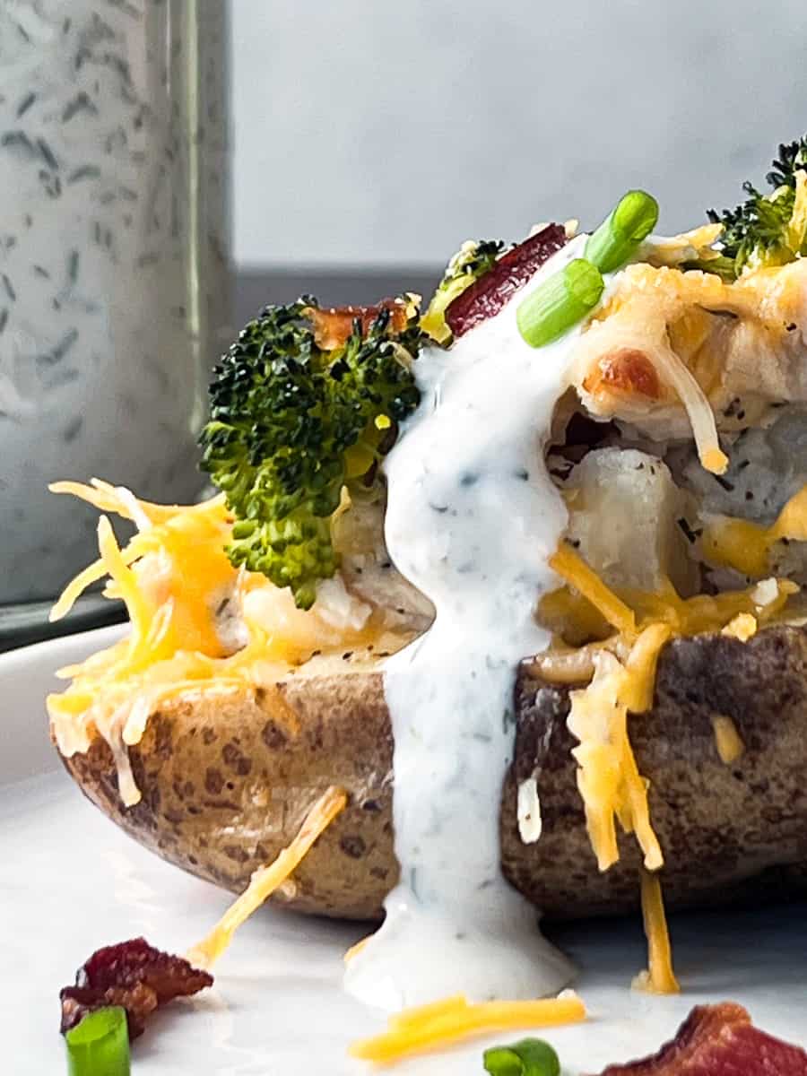 half baked potato topped with ranch dressing.