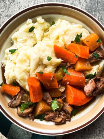 beef stew in a bowl with mashed potatoes.