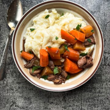 bowl of beef stew with mashed potatoes.