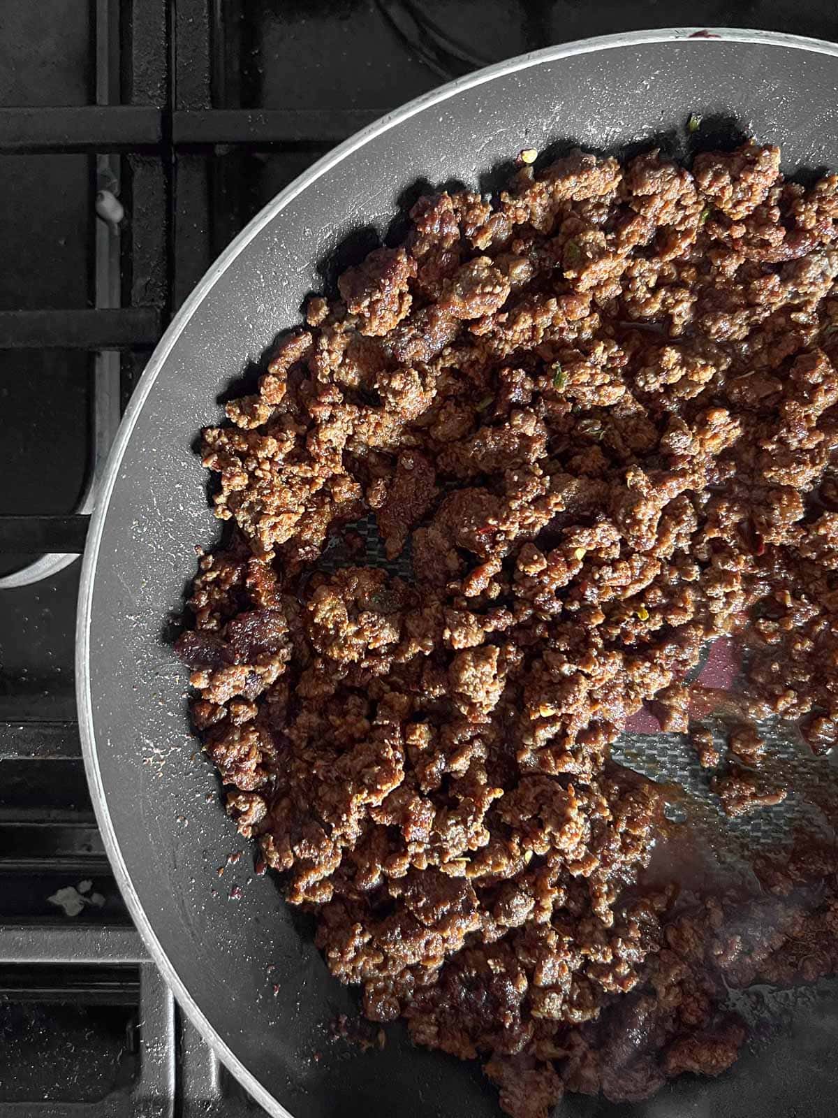 spices mixed into cooked ground beef in a skillet.