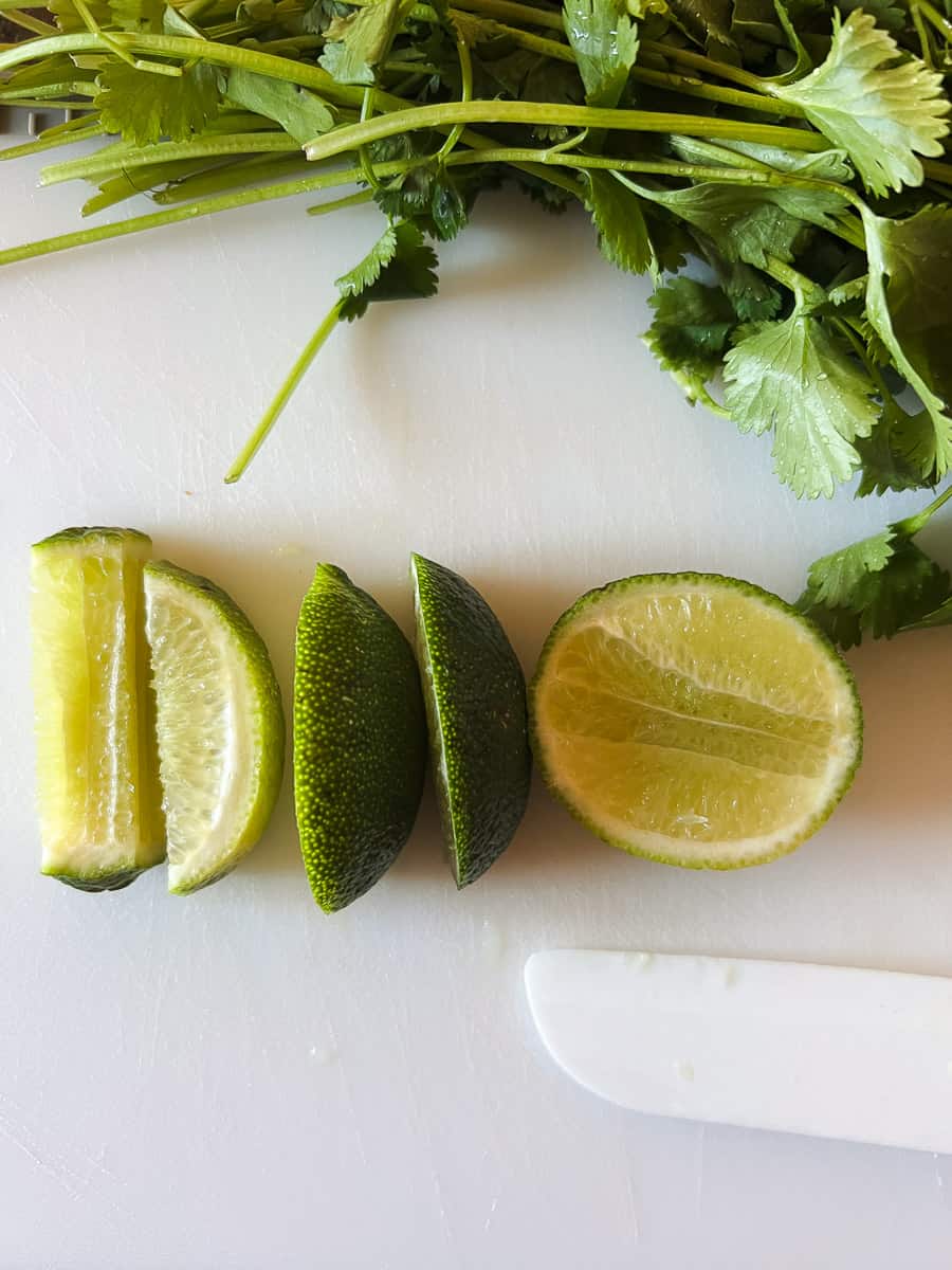 cut lime and fresh cilantro on a cutting board.