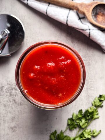 mason jar of pizza sauce with a pizza cutter.