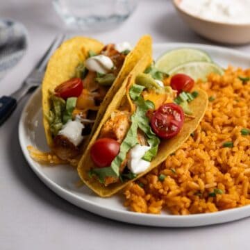 plate with two bags of chicken tacos with a side of Mexican rice.