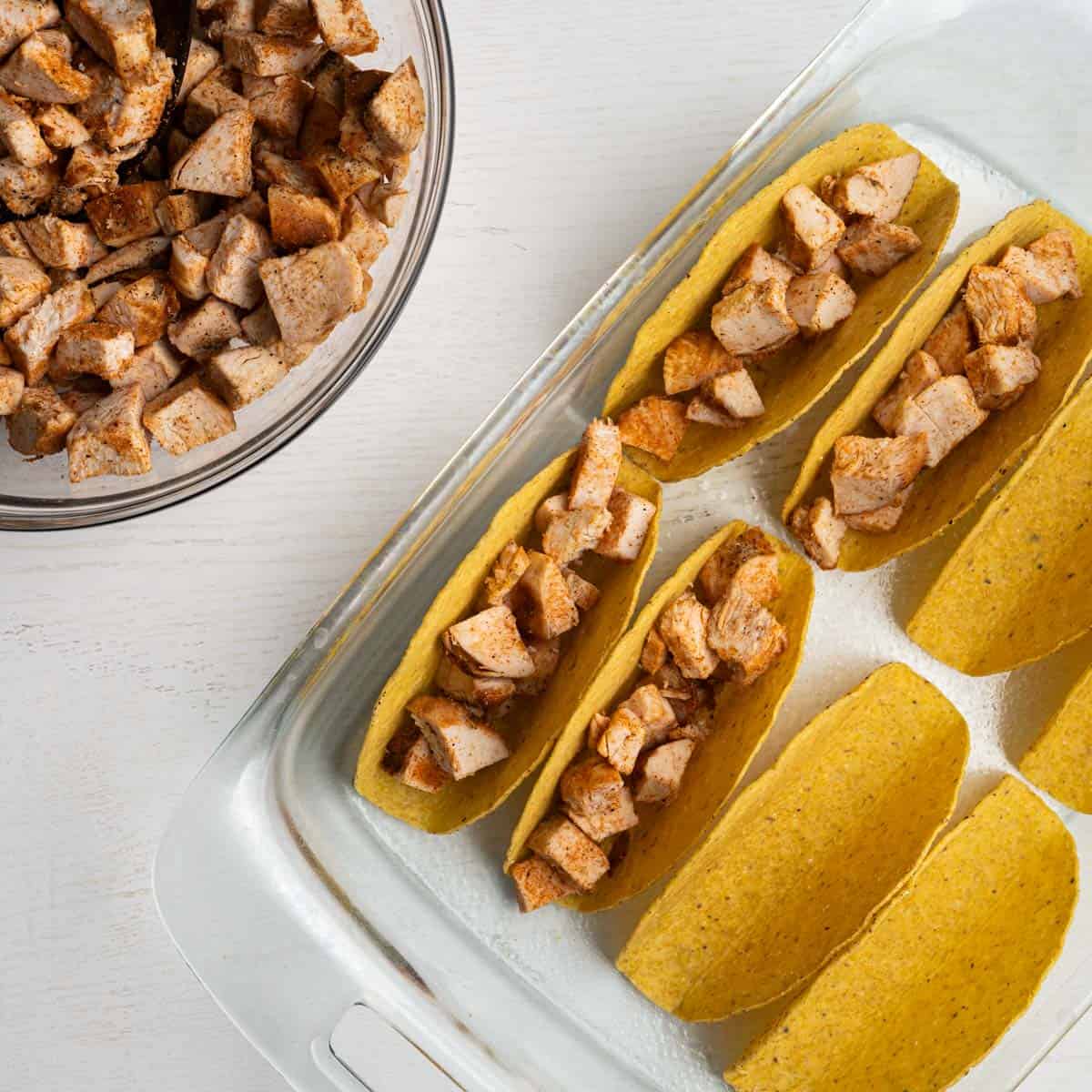 four taco shells filled with seasoned chicken.