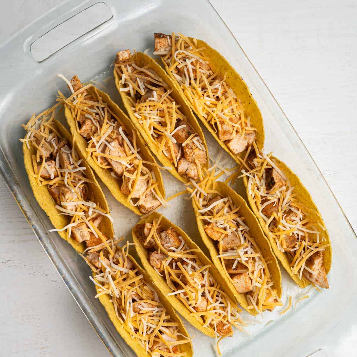 filled taco shells topped with shredded cheese.