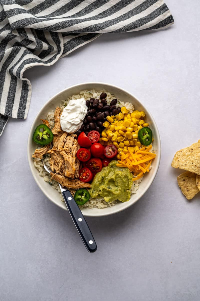 chipotle chicken rice bowl with a fork and handful of tortilla chips.