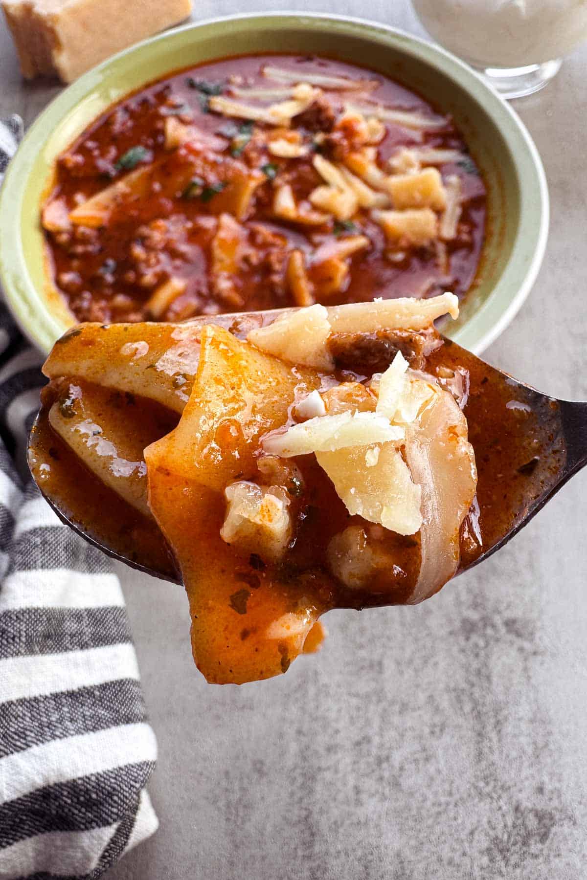 spoonful of lasagna soup topped with parmesan cheese.